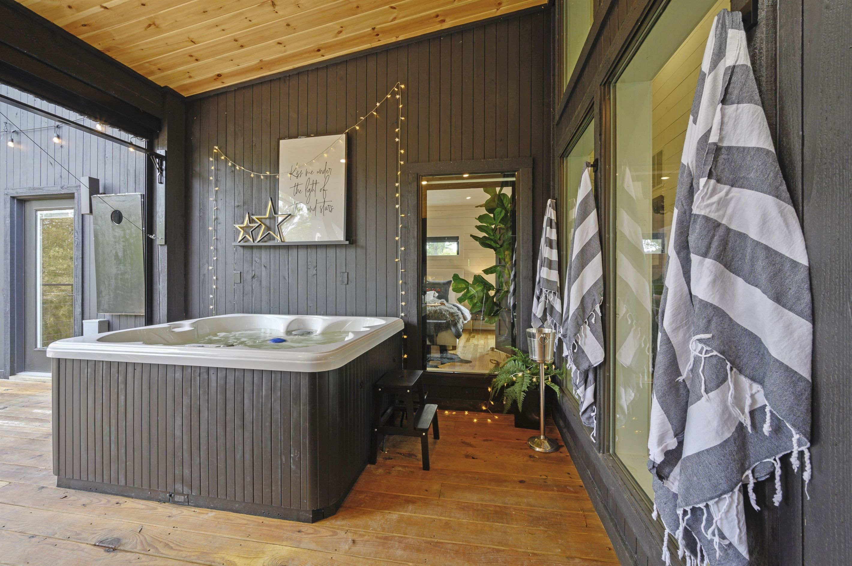 Een moderne badkamer met een ruime badkuip, houten vloer en een spiegel met een handdoek aan de muur.