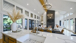 A spacious kitchen with a large island, modern appliances, and a dining area with a fireplace. - Woodland Cabin | Hot Tub · Fire Pit · Forest Views (Broken Bow)