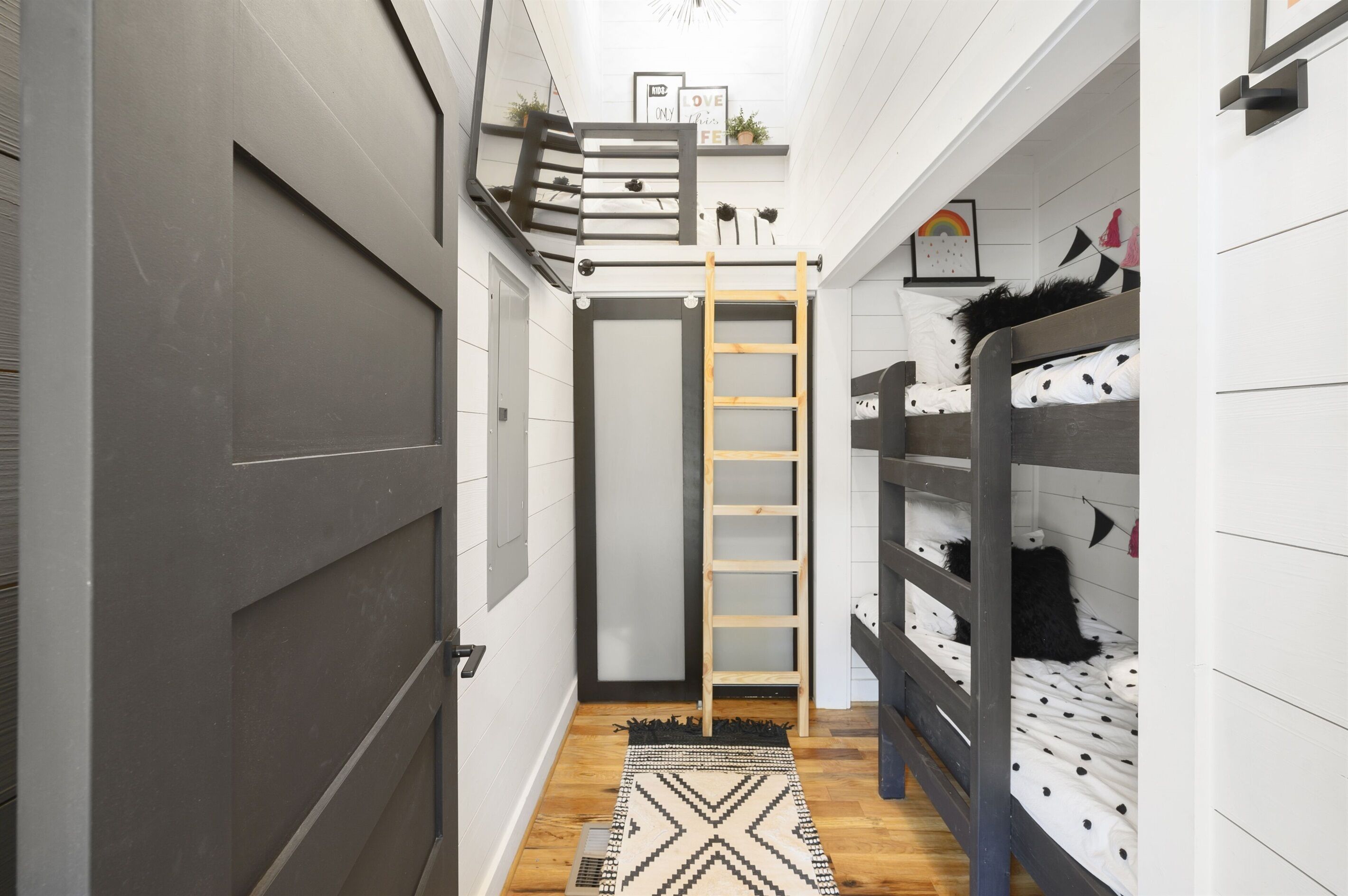 A narrow hallway with bunk beds on one side, a ladder, and a small shelf with decorative items.