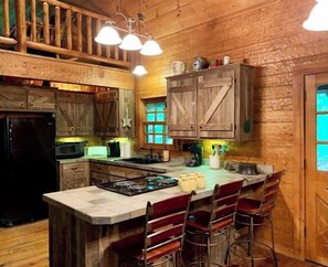 Enjoy cooking in this well-equipped kitchen with a central island, stove, microwave, and refrigerator.