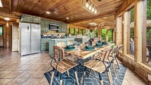 Une cuisine spacieuse dotée de meubles en bois, d’un îlot central et d’un coin repas avec une grande table et des chaises.