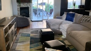 Een moderne woonkamer met een open haard, een bank, een salontafel en uitzicht op het landschap door grote schuifdeuren.