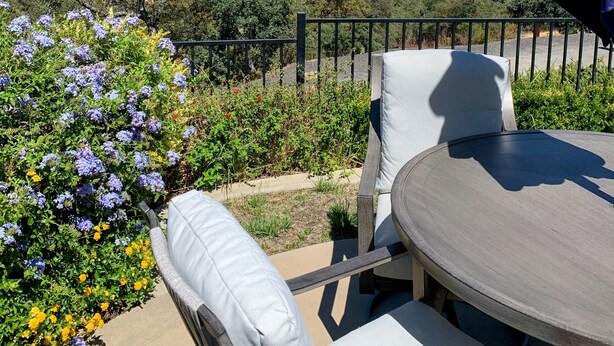 Een terras met een tafel en stoelen, met uitzicht op een mooi landschap met heuvels en een stad in de verte.