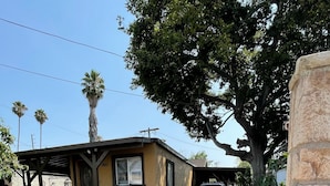 A residential street with a house featuring a porch, a garage, and a parked car. - Casa Cardoza (Los Angeles)