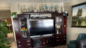 A living room with a large flat-screen TV, a glass coffee table, and a green sofa. - Casa Cardoza (Los Angeles)