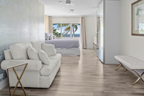 A modern bedroom with a large bed, a sofa, a bench, and a view of the ocean. - Newly updated luxury 4-bed, 4-bath villa with private pool and beach (West Bay)