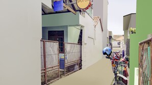 Een smalle steeg met een motorfiets aan de rechterkant, een blauwe helm aan een hek en een bord met de tekst 
