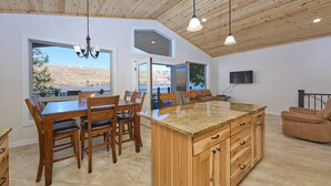 A spacious kitchen with a large island, wooden ceiling, and large windows offering views of the desert.