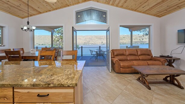 A spacious living area with a large wooden ceiling, a granite kitchen island, and a leather sofa.