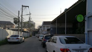 A street view with parked cars, a building with a sign reading "The Leaf Service Apartments," and utility poles with overhead wires. - The Leaf Service Apartment (Chiang Mai)