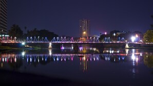 A nighttime view of a bridge with illuminated structures and a reflection in the water. - The Leaf Service Apartment (Chiang Mai)