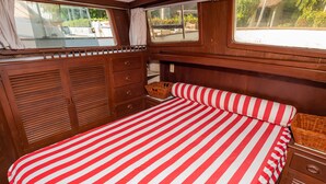 Una cabaña con una cama a rayas, armarios de madera y un ventanal con vistas al exterior.