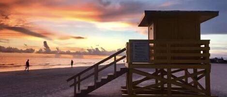 A lifeguard tower on a beach with a sunset in the background.