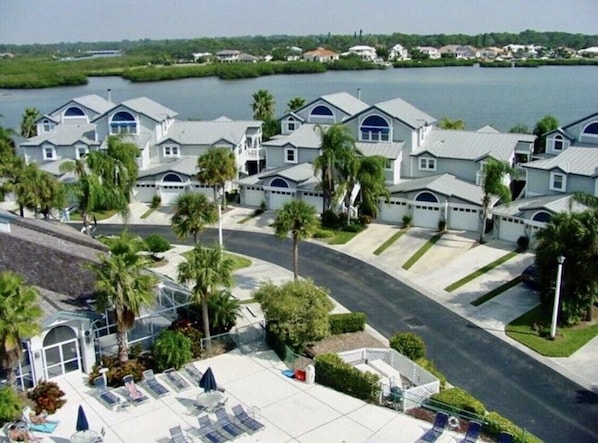 A residential area with multiple houses, a swimming pool, and a view of a body of water.