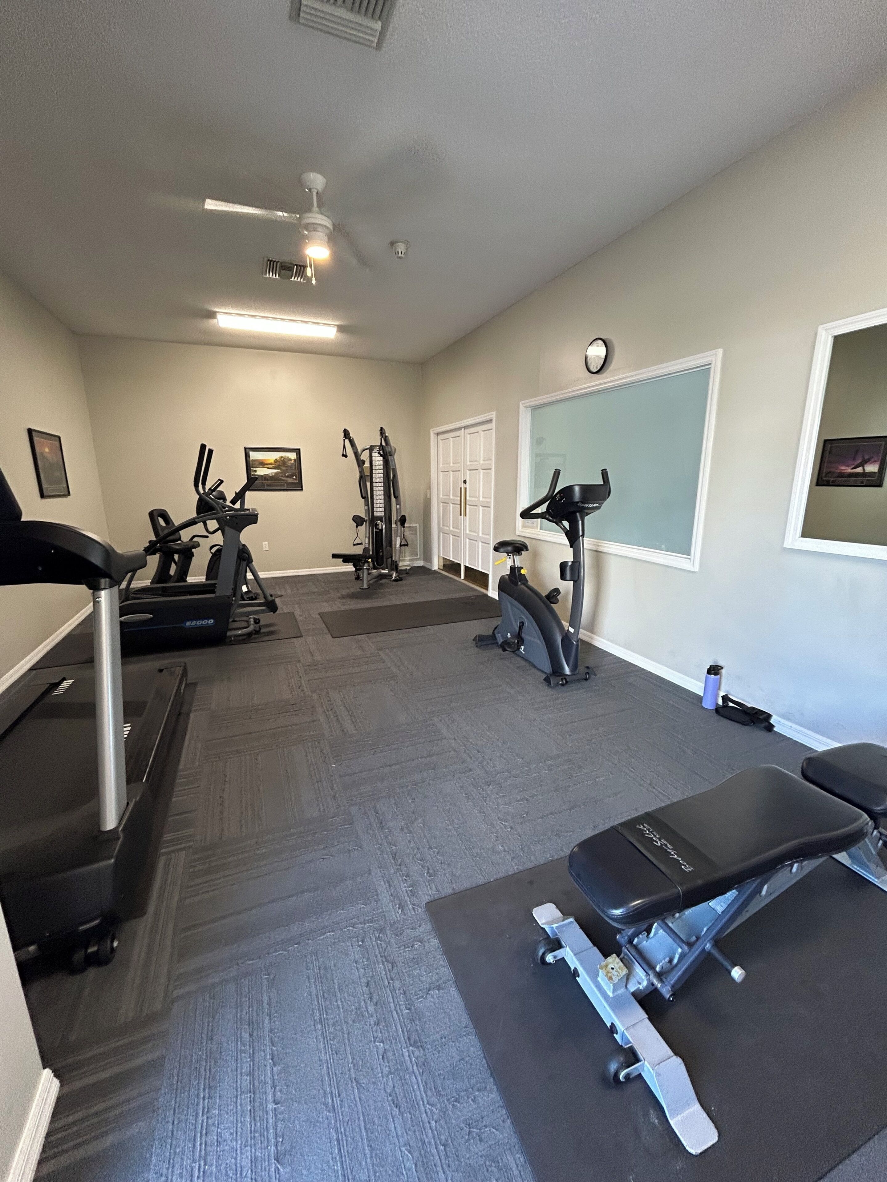 A home gym with exercise equipment, a treadmill, stationary bikes, and a bench.