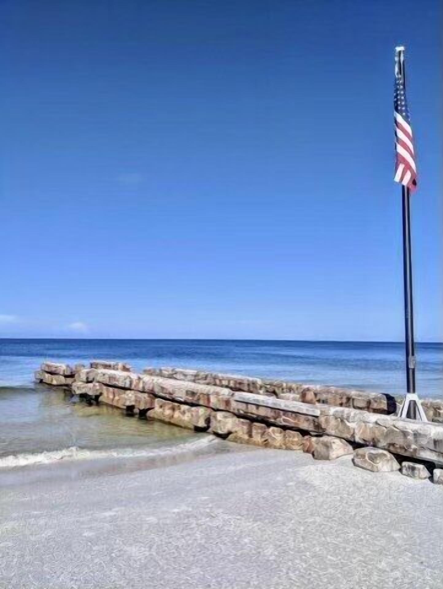 A beach scene with a flagpole and a flag.