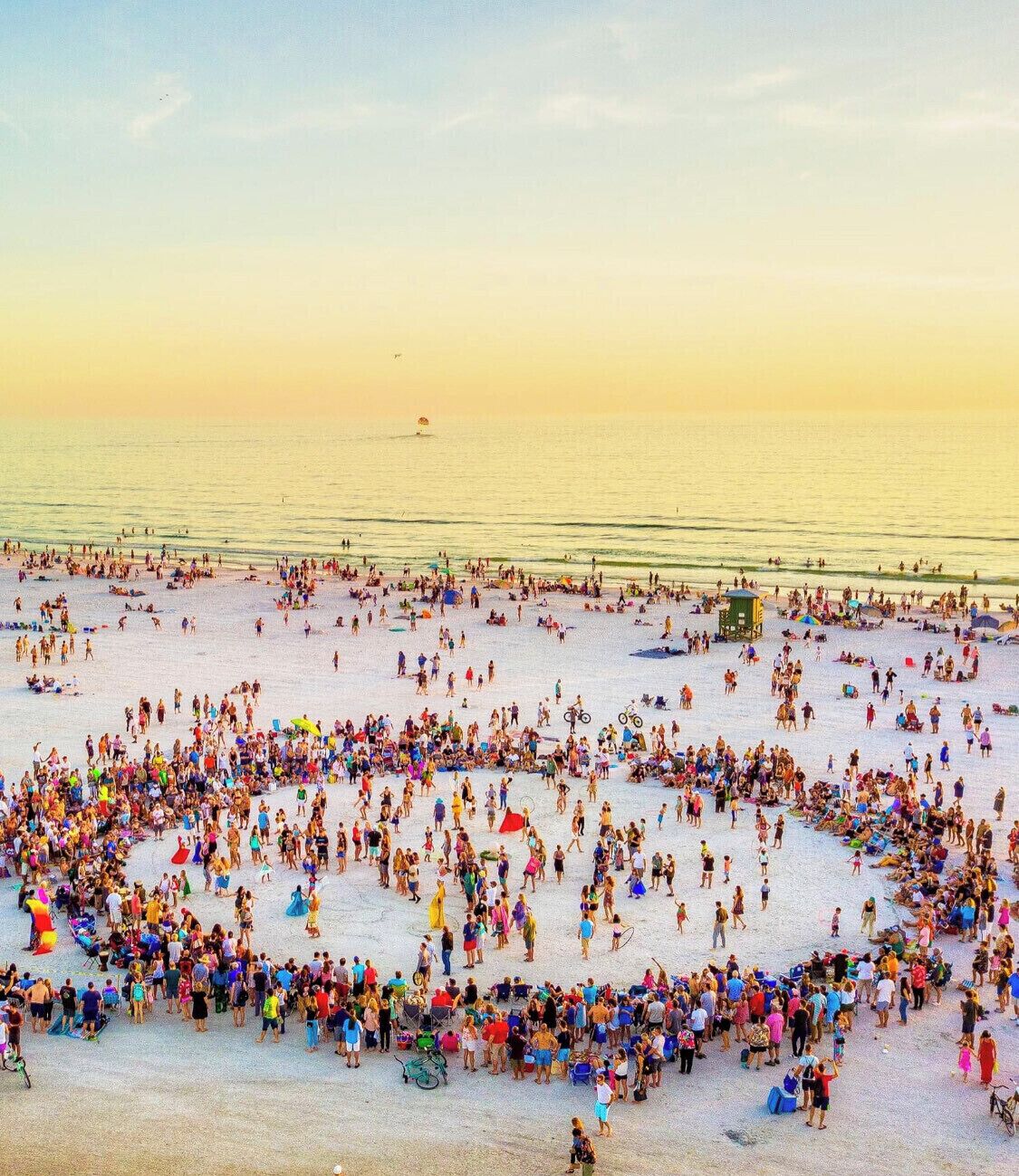 A crowded beach with people and beach equipment.