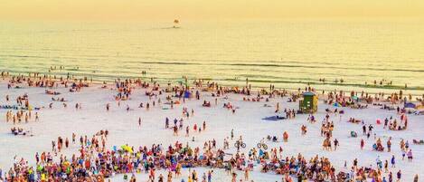 A crowded beach with people and beach equipment.
