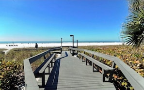 A wooden boardwalk leading to a beach with clear skies.