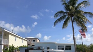 Un barco amarrado en un puerto deportivo, con una casa al fondo.