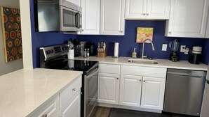A modern kitchen with white cabinets, stainless steel appliances, and a blue accent wall.
