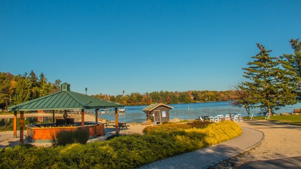A lakeside park with a gazebo, picnic tables, and a small cabin.