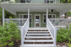 Two-story house with a white porch and staircase leading to the entrance.