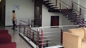 Decoração moderna com escada, estátua de Buda e assentos em vermelho e bege.