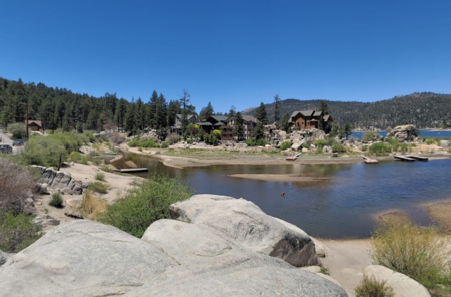 A lakeside lodge with multiple cabins, a dock, and a rocky shoreline.