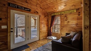 En stuga med träpanel på insidan, komplett med ett bubbelbad, en soffa och en skylt med texten: ”Du är mitt solsken”.