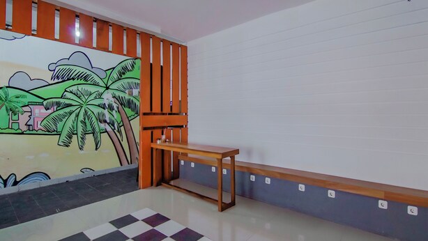 A room with a checkered floor, a wooden bench, a wall with a mural, and a white ceiling. - OYO 89994 Kartini House (Jakarta)
