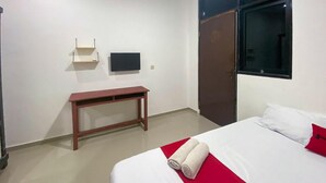 A hotel room with a bed, a wooden bench, a TV mounted on the wall, and a wardrobe. - OYO 89994 Kartini House (Jakarta)