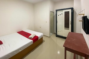 Een hotelkamer met een bed, een klein tafeltje, een kledingkast en een televisie.