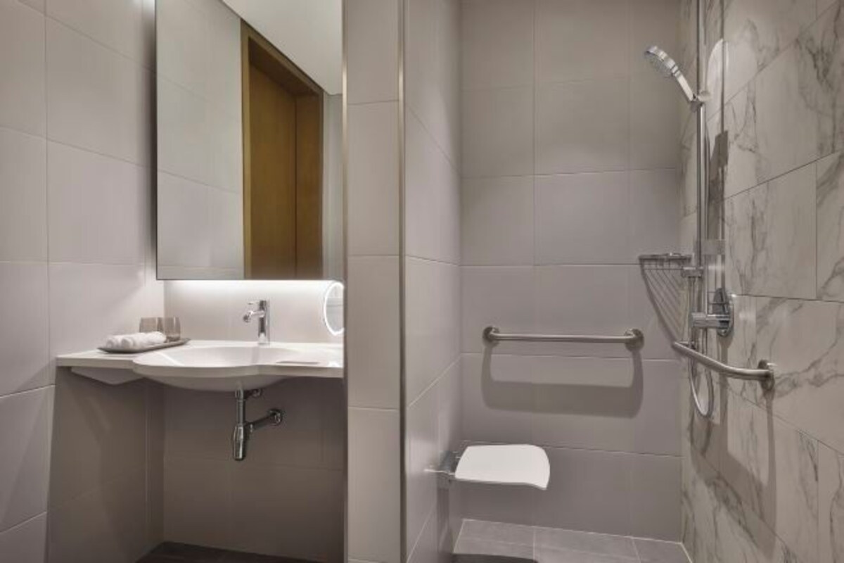 A bathroom with a sink, mirror, towel rack, and shower.