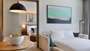 Une chambre d’hôtel avec un lit, une table ronde sur laquelle se trouve un bol, un luminaire suspendu, un tableau et une table de chevet avec une lampe.