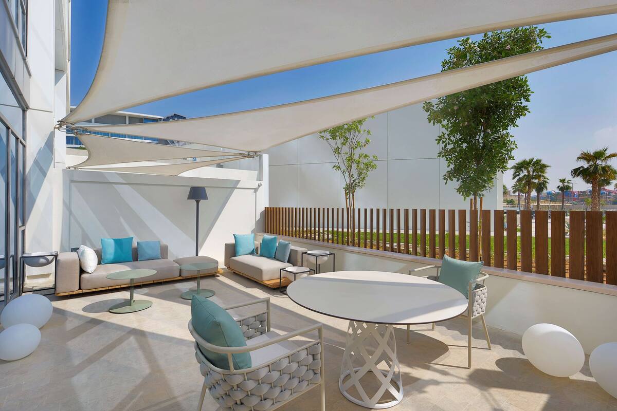 An outdoor patio area with a sofa set, round tables, and chairs.