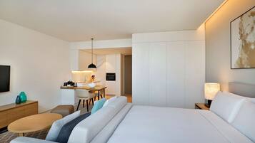 Une chambre d’hôtel avec un grand lit, un bureau avec une chaise, une petite table ronde, un téléviseur et un tableau au mur.
