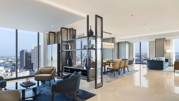 A modern living room with a city view, featuring a sofa, chairs, a dining table, and a bookshelf. - Hilton Bengaluru Embassy Manyata Business Park (Bengaluru)