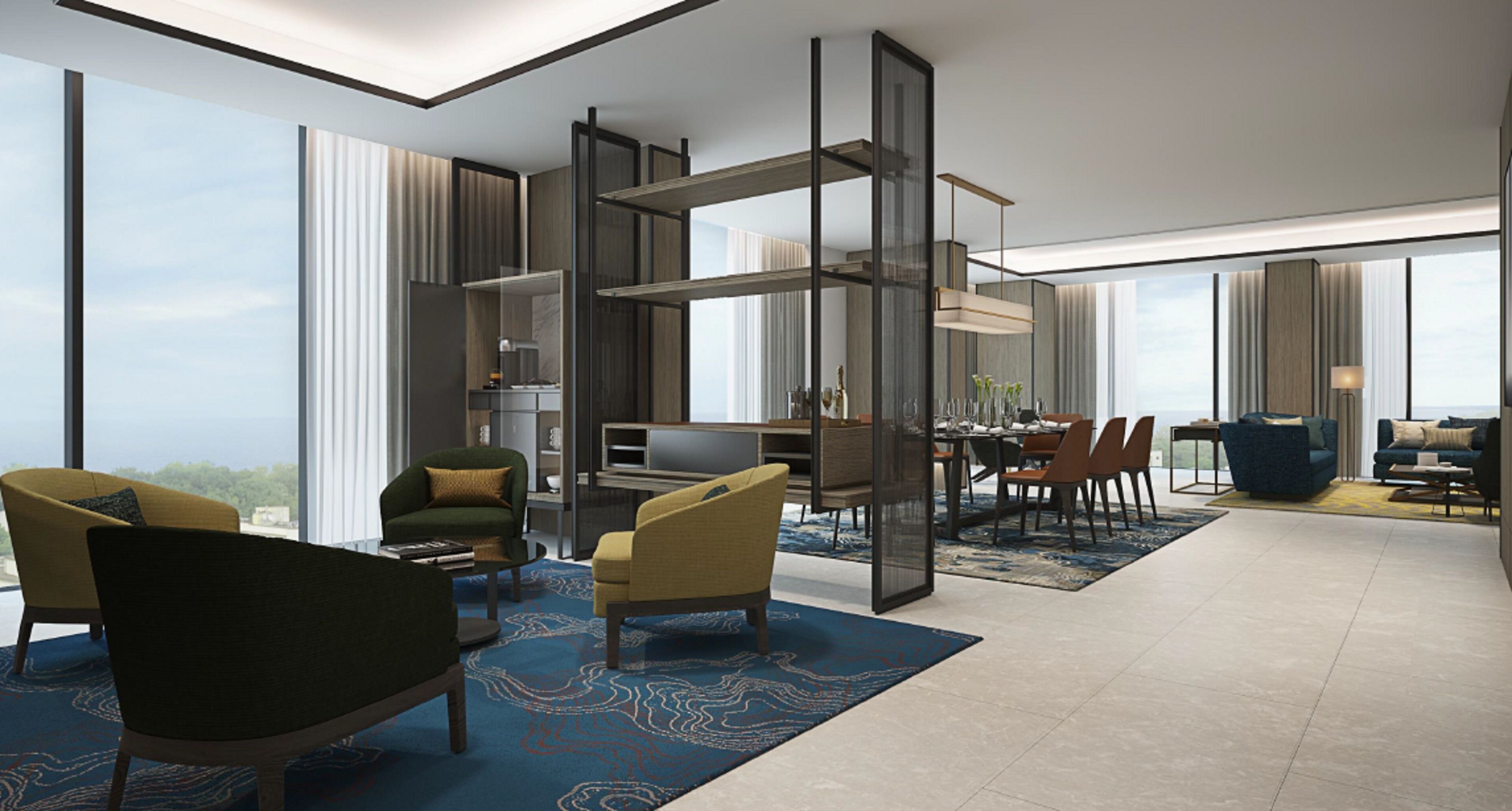 A modern hotel room with a large window, a dining area, and a living space with a sofa and chairs.