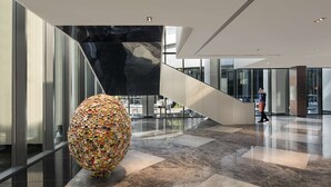 A modern lobby with a large decorative sphere, a staircase, and a glass facade. - Hilton Bengaluru Embassy Manyata Business Park (Bengaluru)