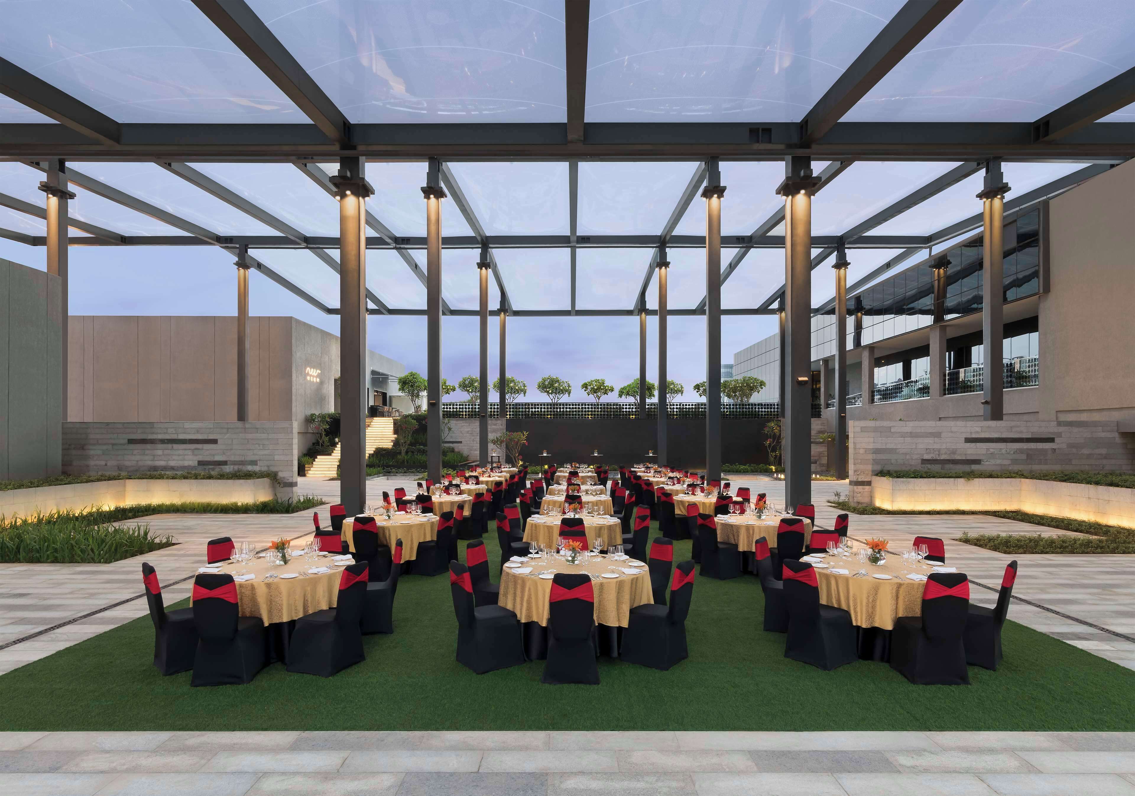 An outdoor dining area with multiple round tables, each set with chairs and table settings.