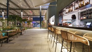 A modern bar area with wicker chairs, a bar counter, and shelves with bottles. - Hilton Bengaluru Embassy Manyata Business Park (Bengaluru)