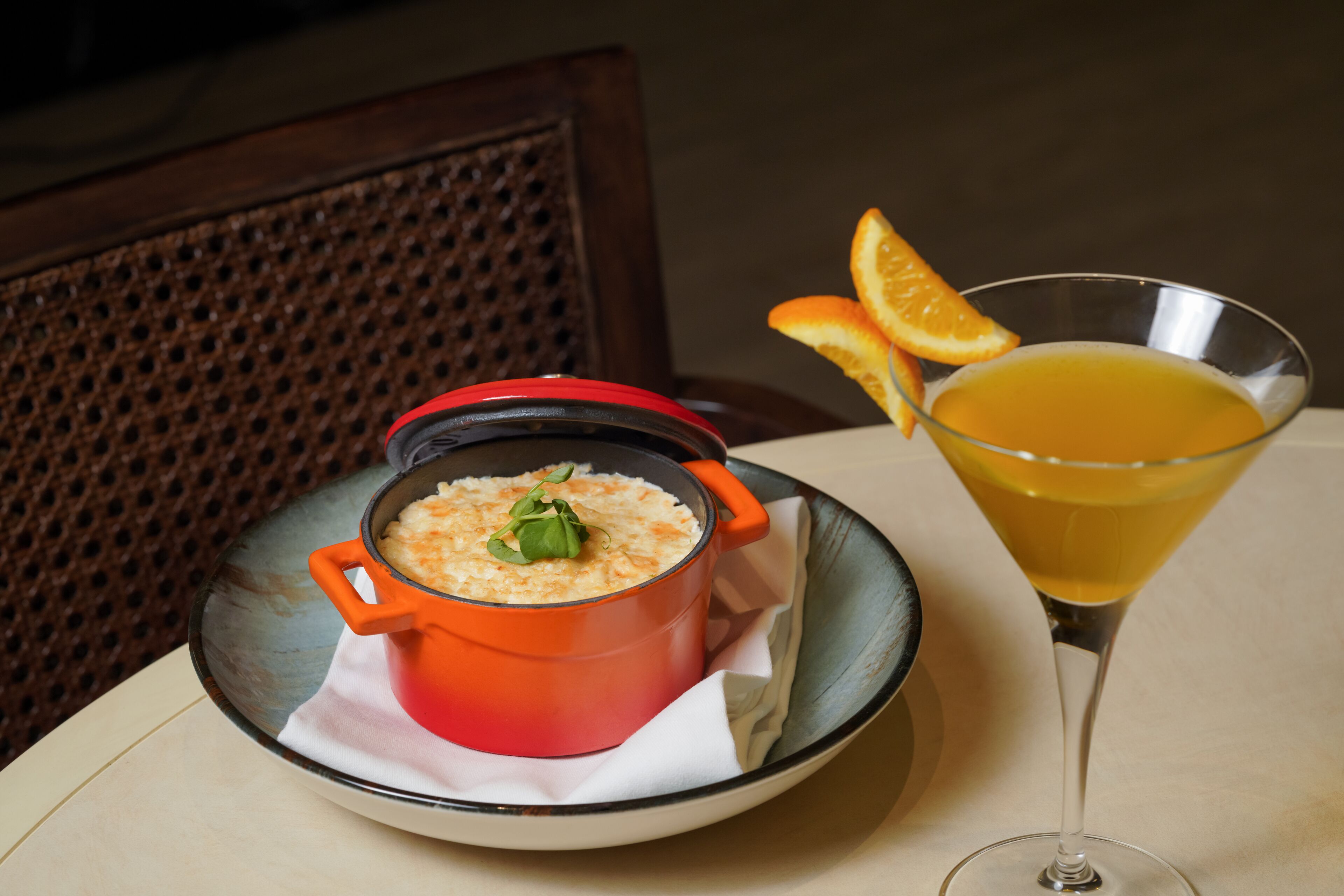 Una mesa con un tazón de comida y un vaso de jugo de naranja.