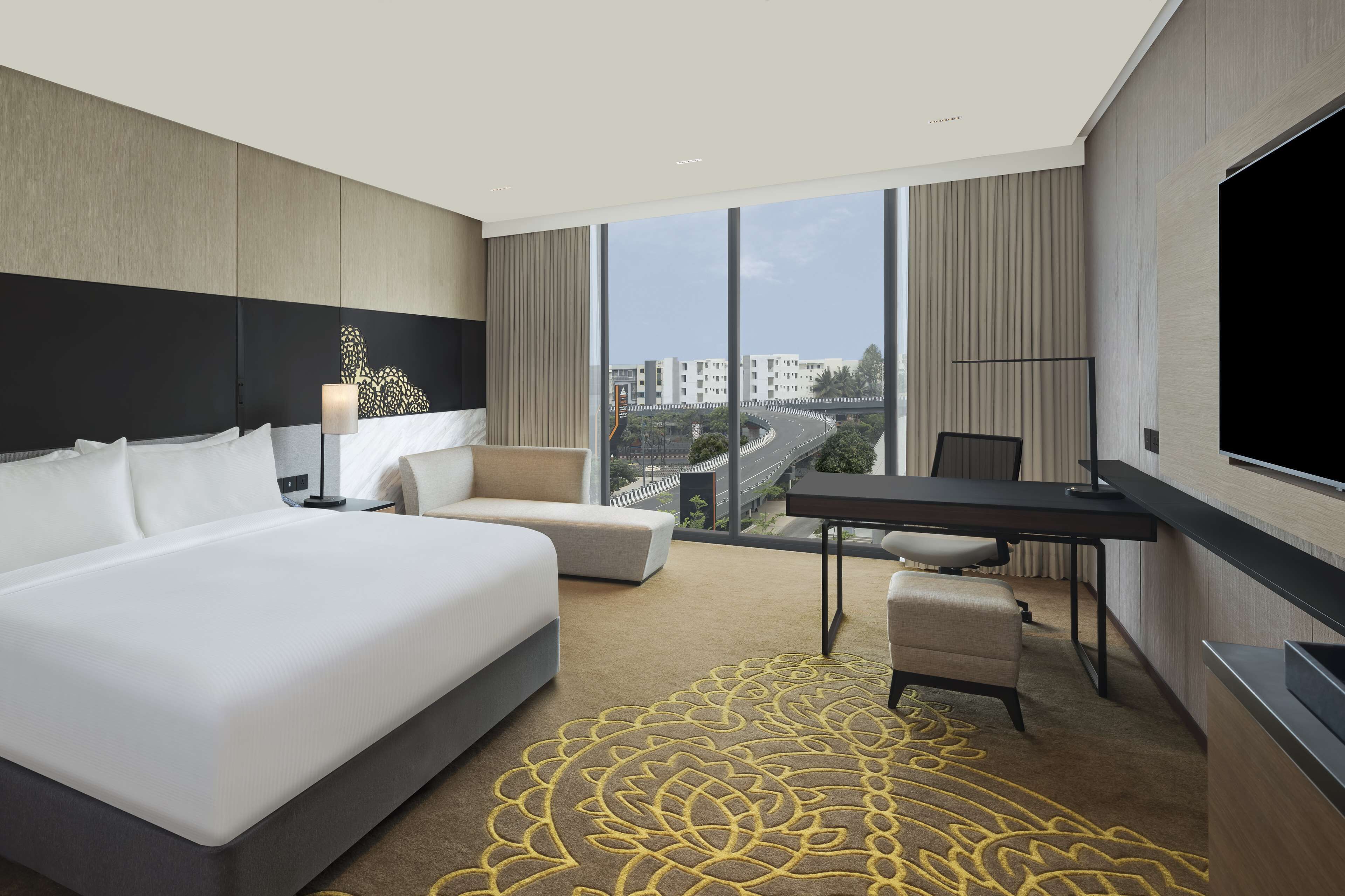 A modern hotel room with a large bed, a desk, and a TV.