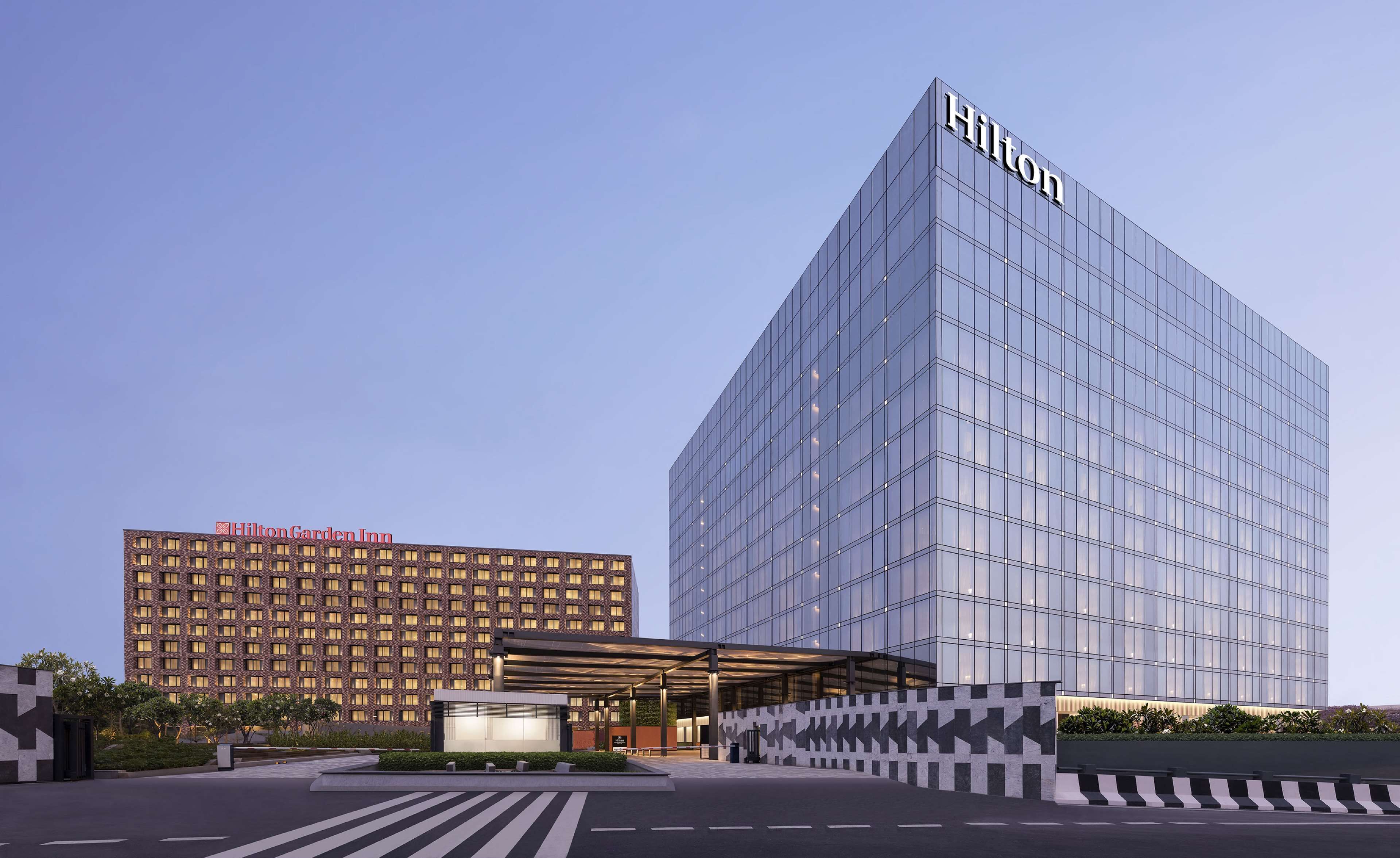 A modern hotel with a glass facade and a prominent Hilton logo.