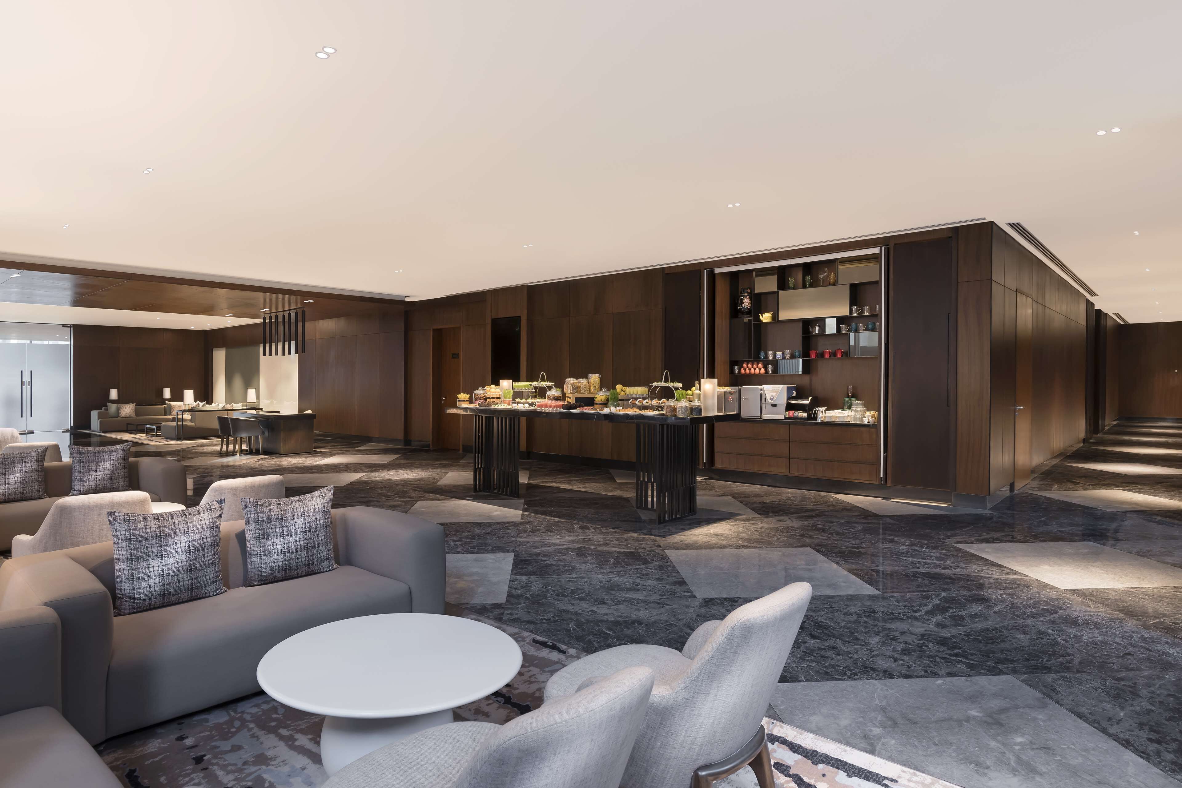 A modern hotel lobby with a seating area, a bar, and a kitchen area.