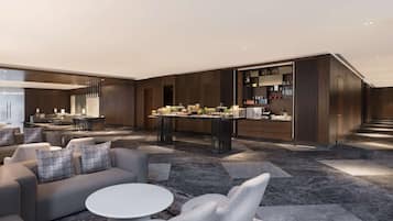 A modern hotel lobby with a seating area, a bar, and a kitchen area.