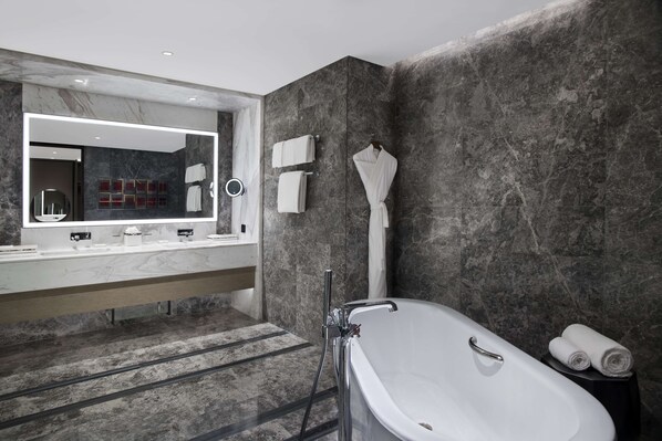 Un baño moderno con un espejo grande, una bañera y un tocador con encimera de mármol.