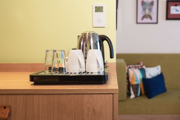 A coffee maker on a wooden counter with two white cups and two clear glasses. - Hampton by Hilton Konstanz (Konstanz)