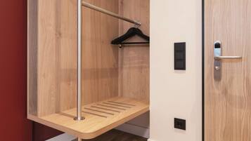 A wooden closet with a metal rod and a black hanger.